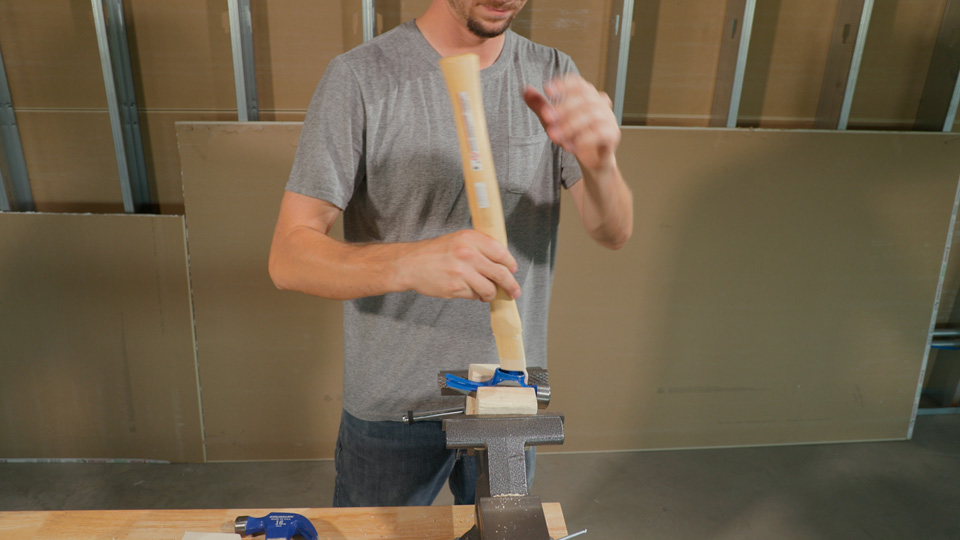 man putting the new handle into the hammer head